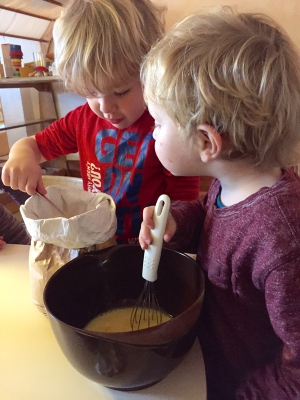 Nu mogen de kinderen om en om een lepel bloem in de mengkom doen, de andere roert met de garde
