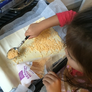 kies een lekkere kaassoort uit en laat je kind deze over het bladerdeeg strooien